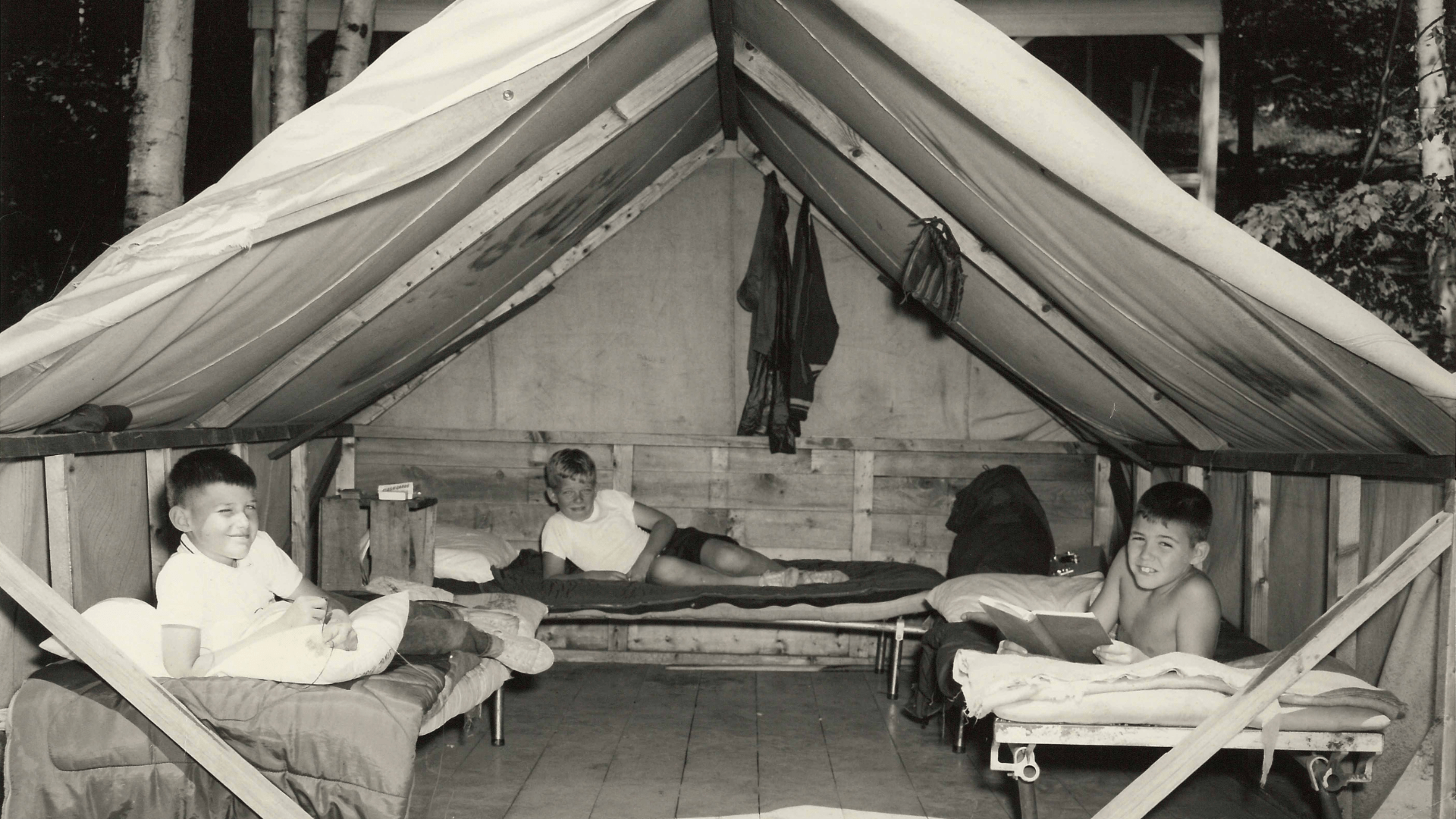 Vintage photo of a camper lying on a cot inside.