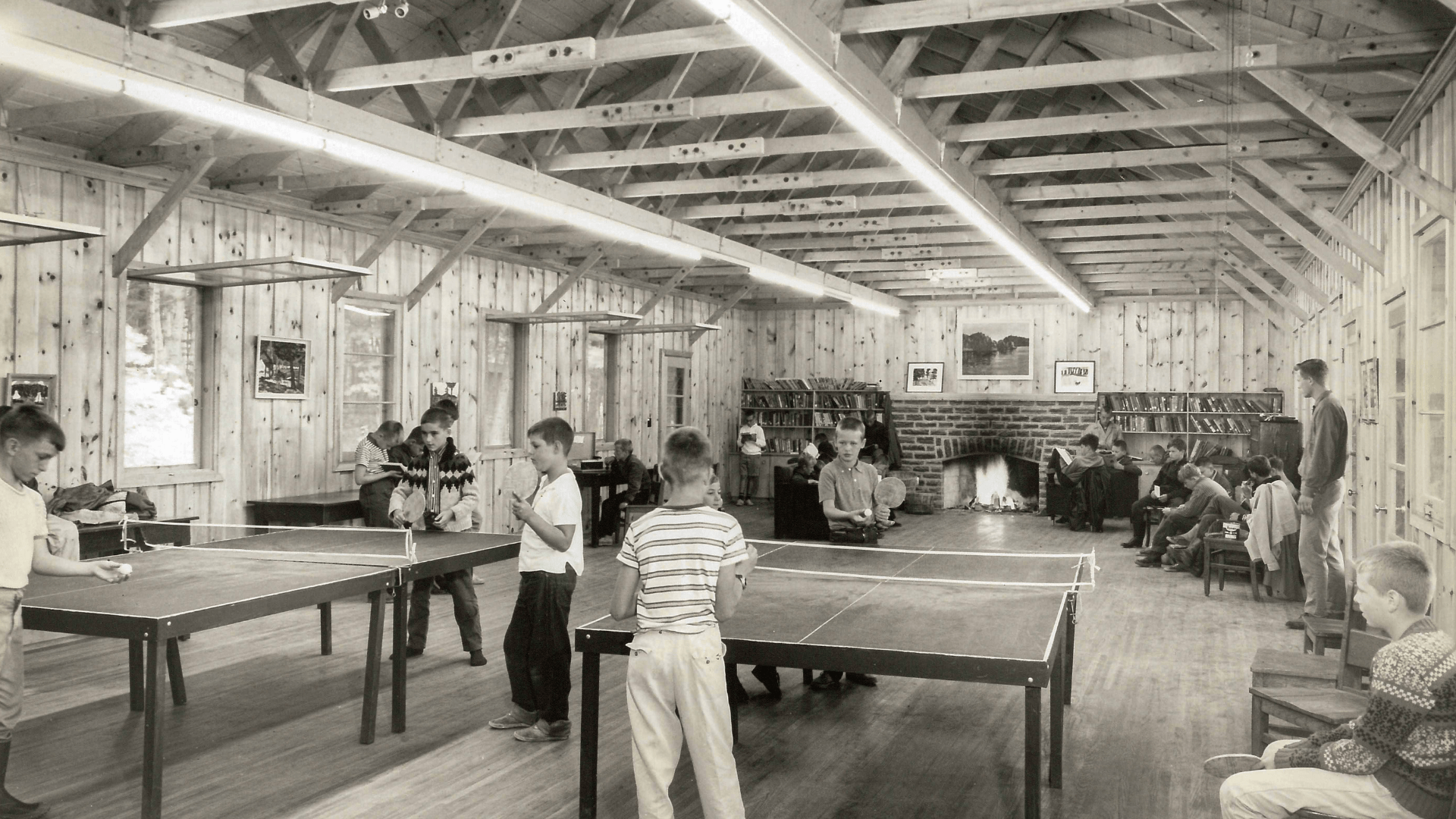 Black and white view of a camp recreation hall interior.