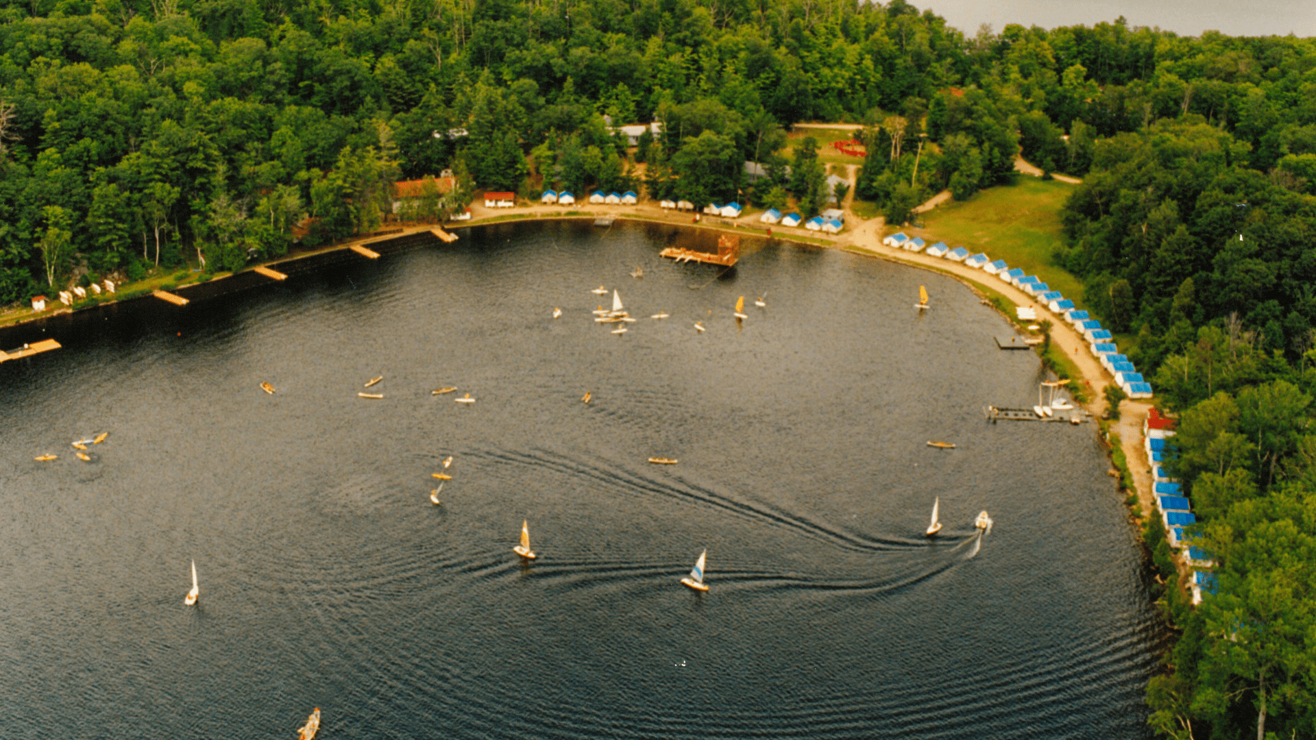 Aerial view of small sailboats on a calm blue lake.