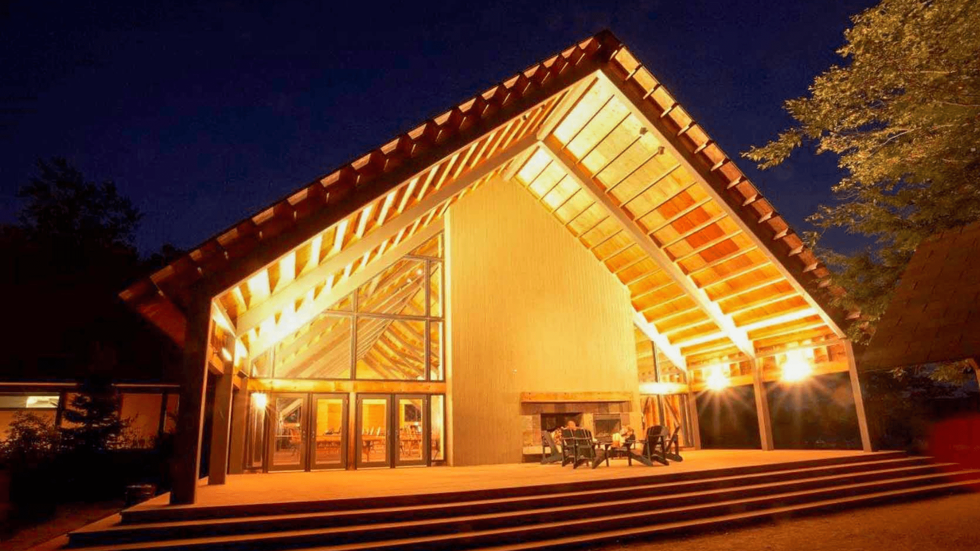 Modern building with large glass windows lit up at night.