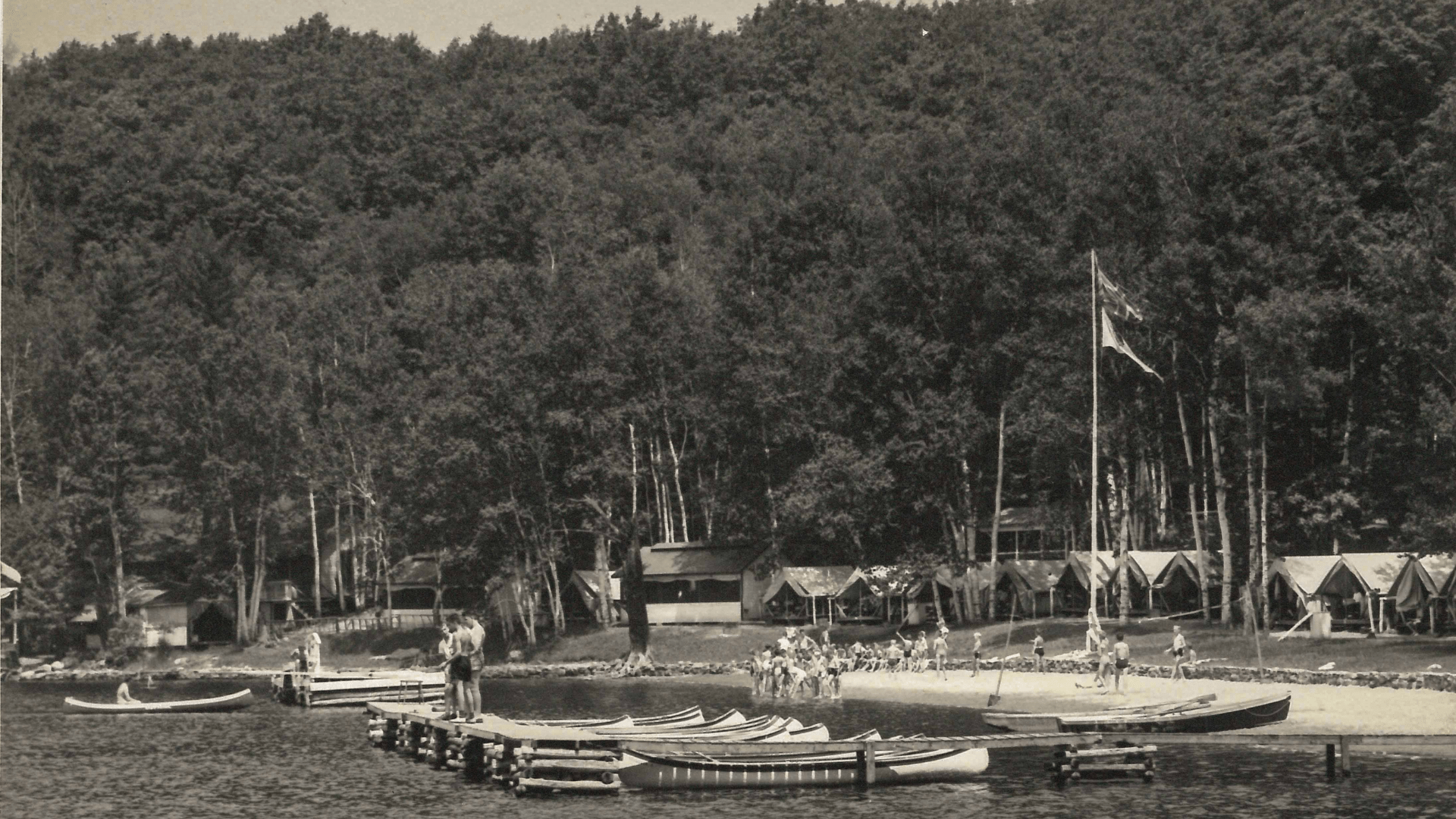 Old black and white photo of canoes by a dock.