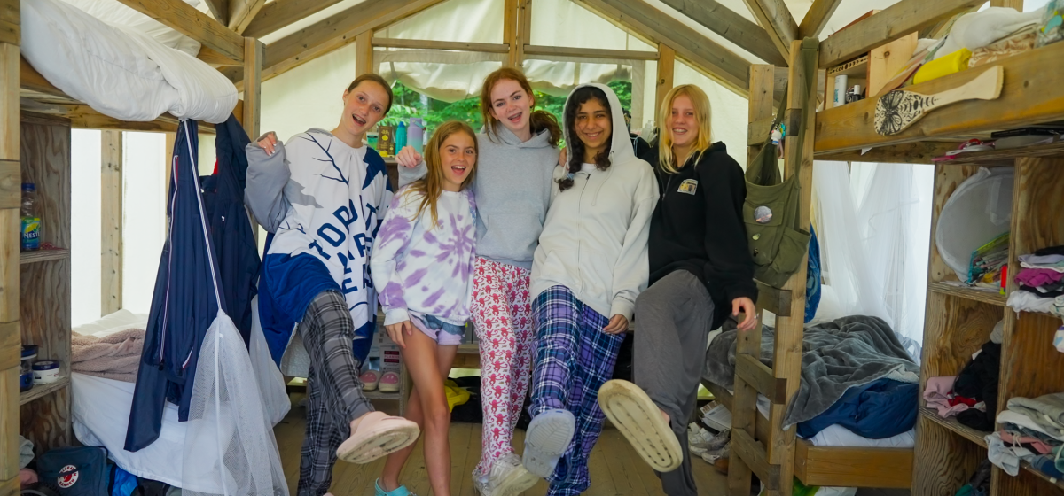 Four girls posing outside a canvas tent.